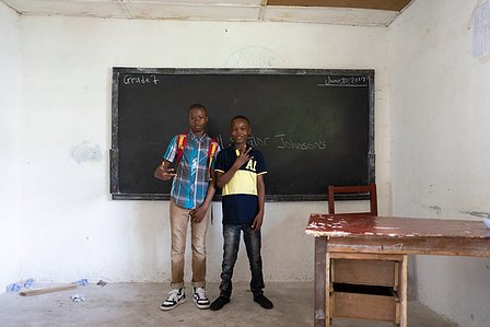 Two young boys studying in seventh-grade standing beside a desk and chair shot by Ashish Gurbani best travel photographer based in Mumbai India.