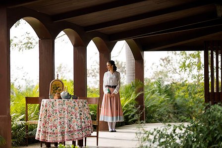 farm girl standing at a distance waiting for her husband to join her for lunch in a themed photoshoot oraganised by creative advertising photographer for a clothing brand shoot based in pune india