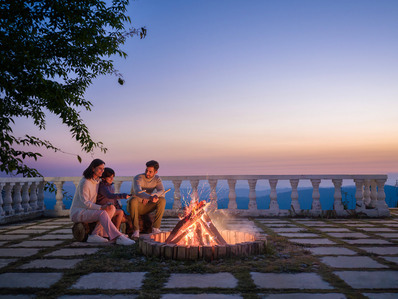 a young family enjoys a bonfire experience at the hilltop during sunset 
