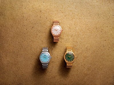 product photoshoot of three metal strap watches placed on a concept desert sand photographed in studio