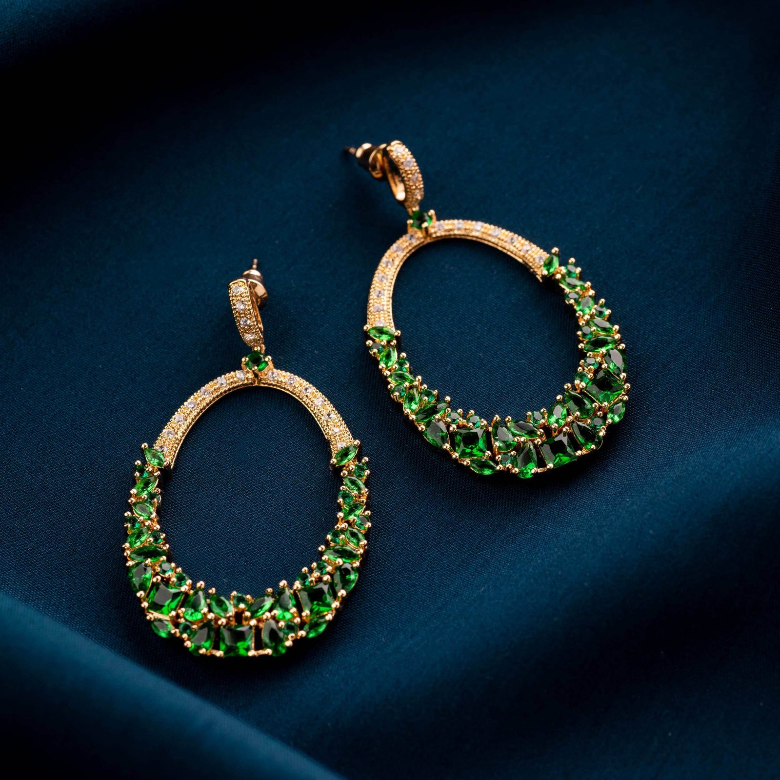a professional conceptual jewellery shoot of green emeralds on wavy blue cloth shot by best fashion photographer ashish gurbani based in mumbai india