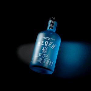 a beautiful bright seqer gin bottle shot on a dark black background by best creative alcohol bottle photographer based in pune india