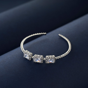 white gold handmade bracelet with rare solitaire stones in emerald cut shot on blue background for a specialised luxury jewellery brand concept studio shoot by best product photographer ashish gurbani based in pune india