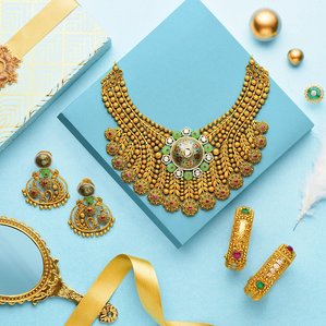 a jewellery photoshoot showcasing a gold necklace, bangles and earrings studded with different precious stones on a blue background with props for a popular jewellery brand by India&amp;amp;#x27;s leading product photographer based in Delhi.