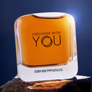 a studio conceptual photoshoot of an Emporio Armani stronger with you perfume orange bottle shot on blue background by professional commercial photographer specializing in luxury product pricing shoot based in pune india