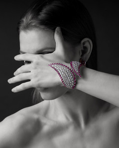 a stunning female model covers her face with a charming hand bracelet studded with best diamonds photographed for an advertising brand campaign