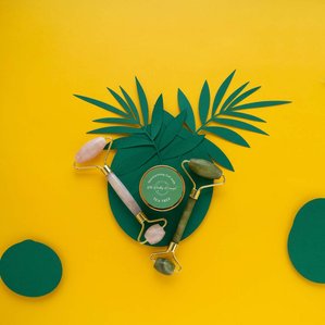 rose quartz face roller jade face roller and vitamin c gel skin care products in a conceptual olive green and yellow background photoshoot for leading brand campaign by  indias top jewellery photographer  based in pune india
