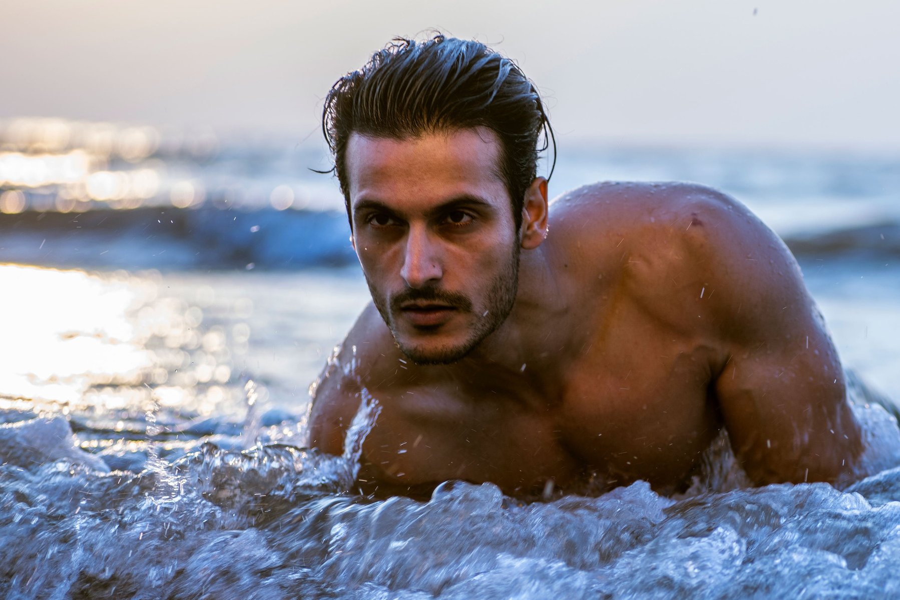 a close up portrait of model angel singh lying down on the beach in the water during sunset shot by best fashion and ad photographer ashish gurbani based in Mumbai india