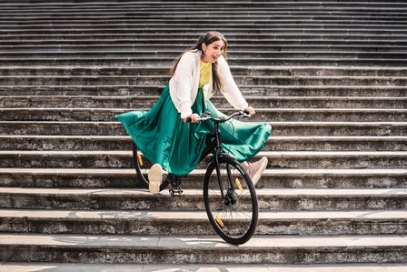 young beautiful girl riding a bicycle down a staircase having fun for cycle tyre brand photoshoot by leading advertising photographer at the mumbai famous library