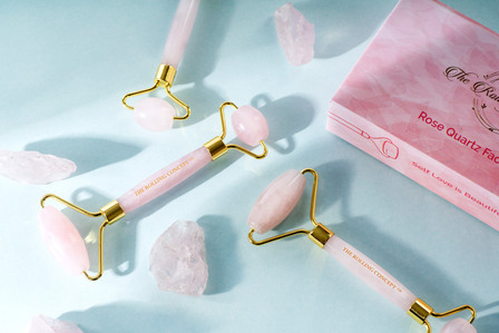 a professional photoshoot of high end rose quartz face roller on sky blue background with ray of light flowing in creative photography setup with best cosmetic product photographer ashish gurbani based in pune india
