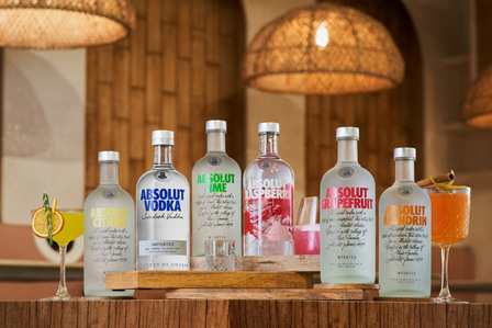 A group shot of neatly styled Absolut vodka bottles with a variety of cocktails placed on top of a wooden table was captured by the best brand photography in Mumbai, India.