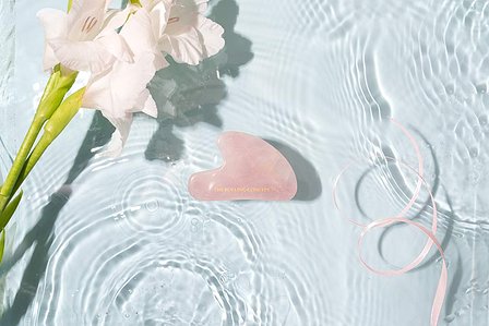 rose quartz gua sha placed in a fish tank with water waves and splashed shot by leading jewellery photographer based in mumbai india