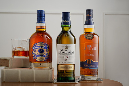 A group of three different bottles kept neatly on white books in front of a white wall captured by lifestyle photography in Pune, India.