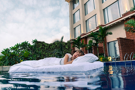 a model lying down in a floating mattress on a swimming pool photographed for leading westin marriott bonvoy hotel brand campaign photographer based in pune india