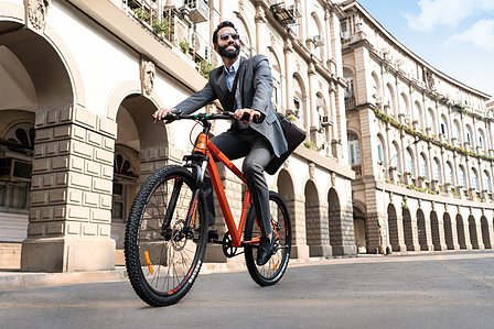a young dashing man rides his orange cycle to work in a full suit for a commercial brand photoshoot by best lifestyle photographer based in Mumbai india