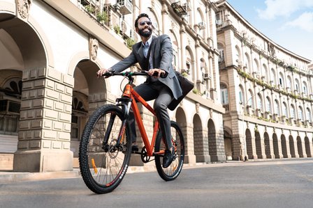 a young dashing man rides his orange cycle to work in a full suit for a commercial brand photoshoot by best lifestyle photographer based in Mumbai india