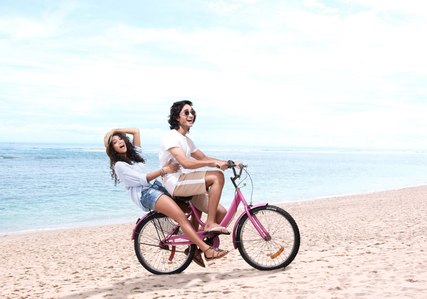A couple riding a cycle on the beach on sunny summer noon for brand campaign shoot with top advertising photographer based in Mumbai India.