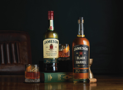 Jameson whiskey bottles styled in a group shot on a table top with a couch, books and a cork serving as props, captured by jewelry photographer in Pune, India