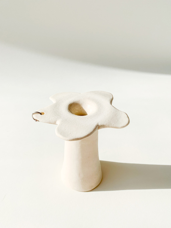 	 a three-candle holder that has a hole in the middle glazed in a marshmallow white. small white flowers are sticking out of the middle candle hole.