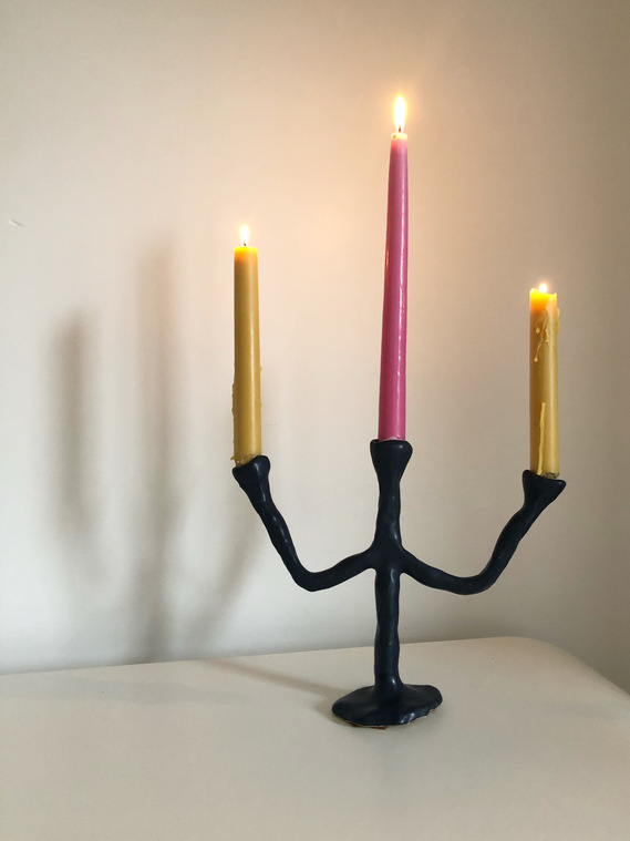 a dark navy blue, three-tiered candelabra holding three lit candles