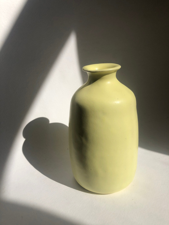  a small pastel yellow  ceramic jug with a flare lip