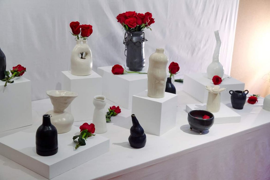 a white-clothed table with multiple ceramics in black and white scattered about with red roses