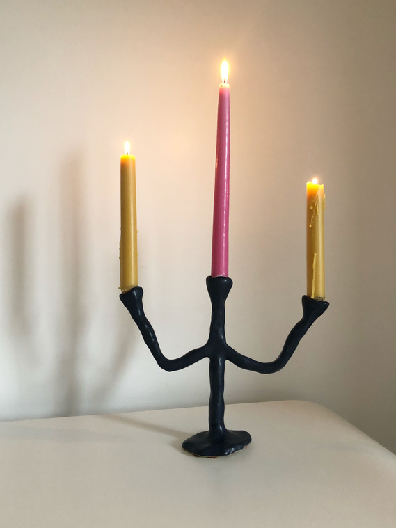 a dark navy blue, three-tiered candelabra holding three lit candles