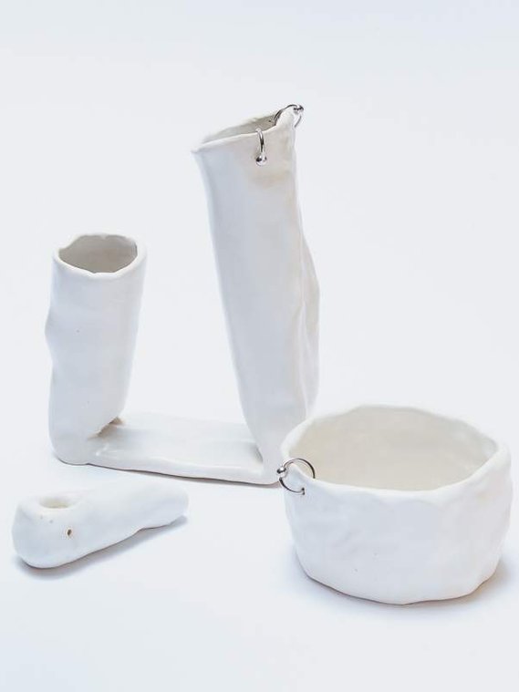 three ceramic pieces, on the left is a pipe, behind it is a double vessel pierced twice, and  on the right is a pinched bowl pierced with one silver hoop. all three pieces are glazed in a marshmallow white.