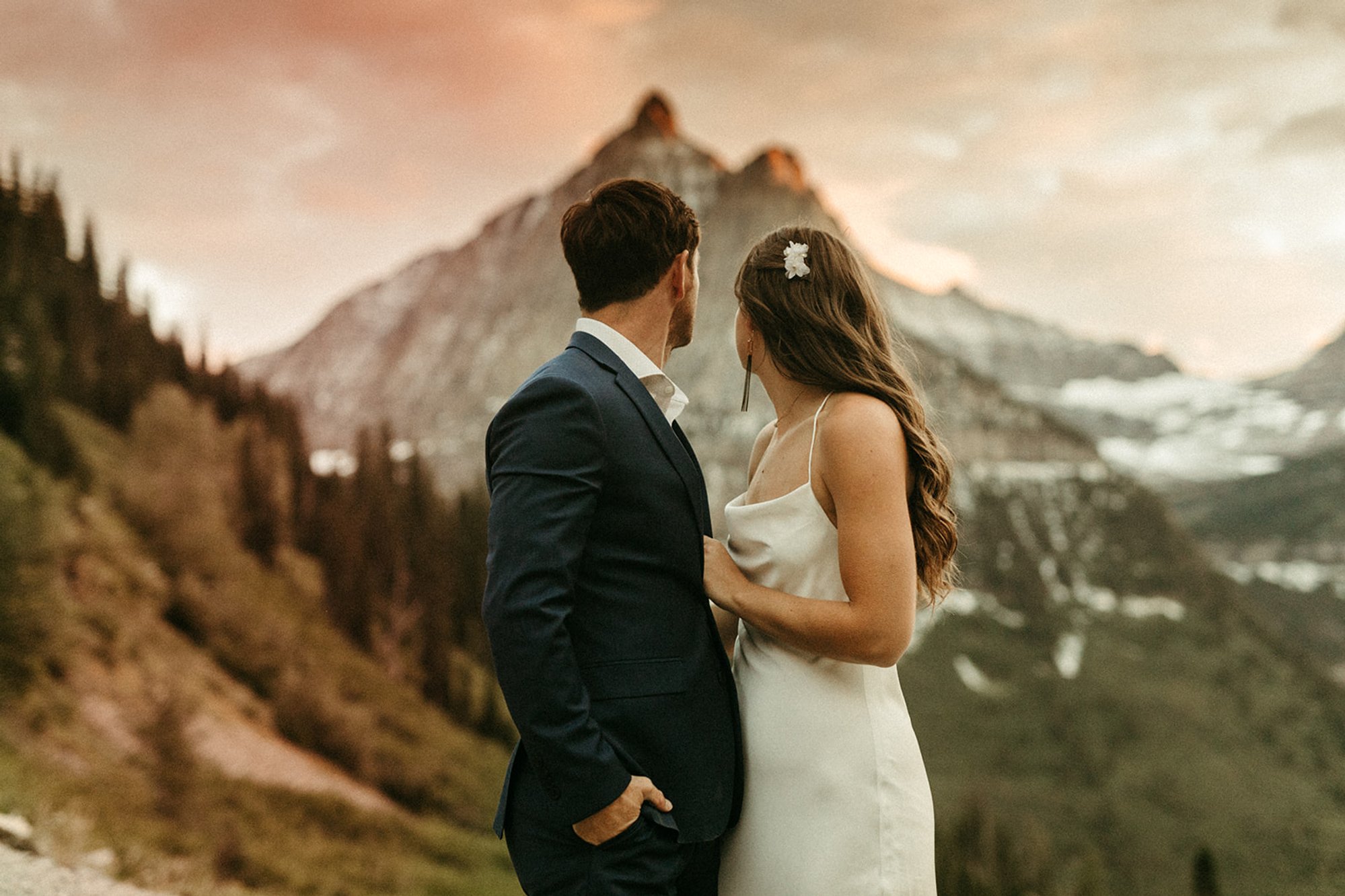 Bride and Groom on their adventure elopement, standing at Big Bend looking out at Oberlin peak in Glacier National Park, Montana.