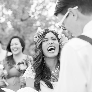 Bride wearing flower crown laughing while reading her vows during her backyard wedding in Montana. 
