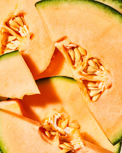 Closeup image of fresh orange melon with seeds and green skin.