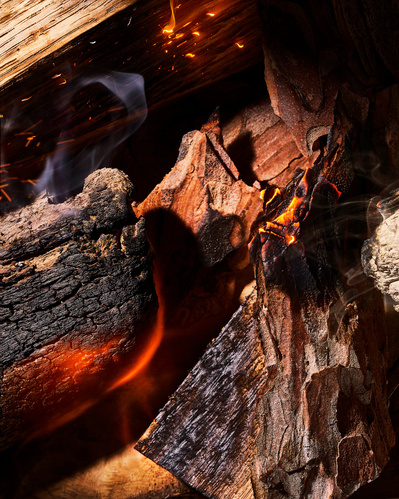 Close-up image of burning wood, smoke and char.