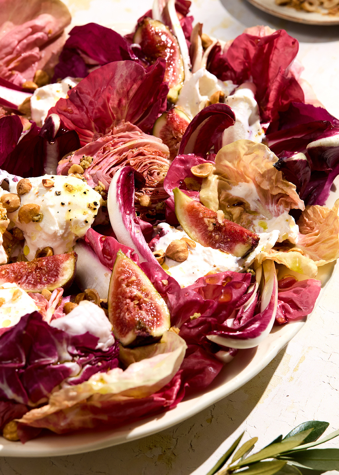 Hard sun with crisp light and shadows on a rustic surface. Featuring raddichio, figs, burrata, hazelnuts and olive oil. Photography by Lol Johnson. Food prep and styling by Iona Blackshaw. Props by Nuala Sharkey.