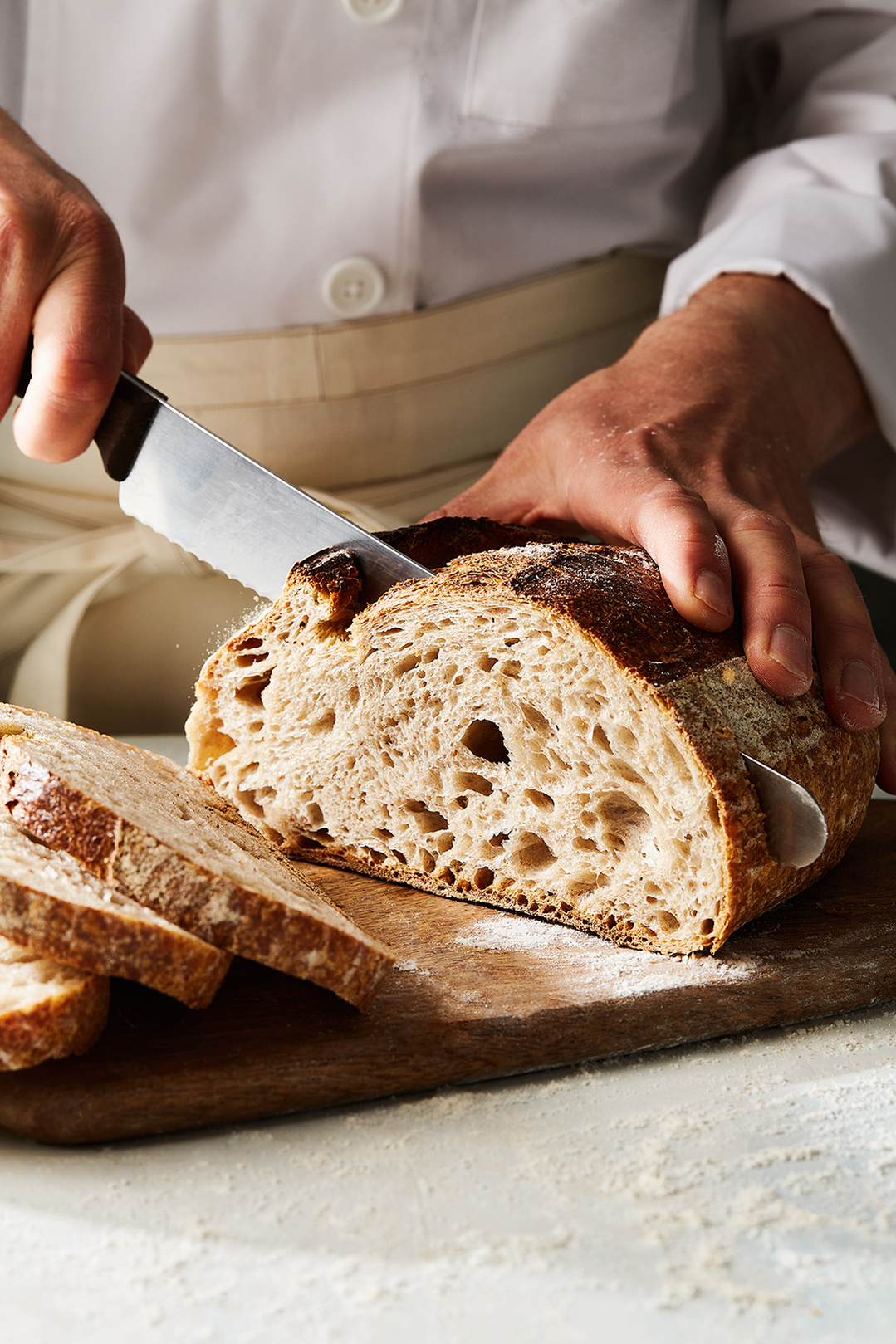 Baker slicing sourdough bread for Hilton in-house deli brand Do Deli. Photography by Lol Johnson. Food Prep and styling by Iona Blackshaw. Recipe development by Jane Alty.