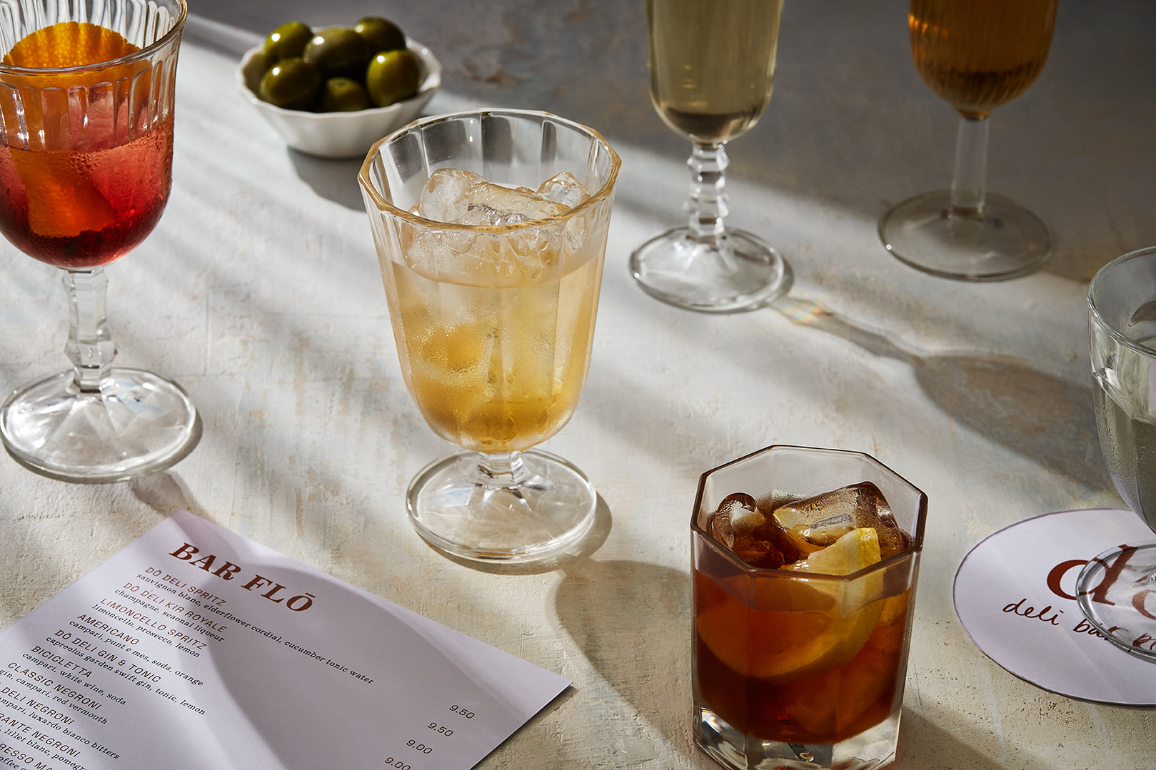 An selection of summer drinks on a sunny table for Do Deli @ Hilton. Photography by London based food and drink and lifestyle photographer Lol Johnson. Drink prep and styling by Iona Blacksmith.