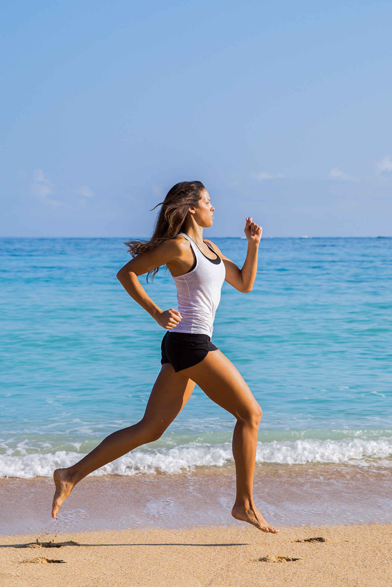 A strong woman runs on the beach in Maui. 
