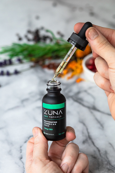 Hands use eye dropper to sample Zuna serum. 