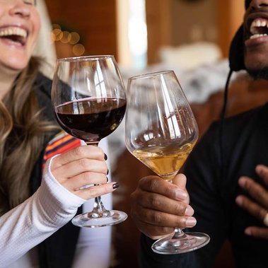 Two friends cheers and laugh drinking XOBC wines.