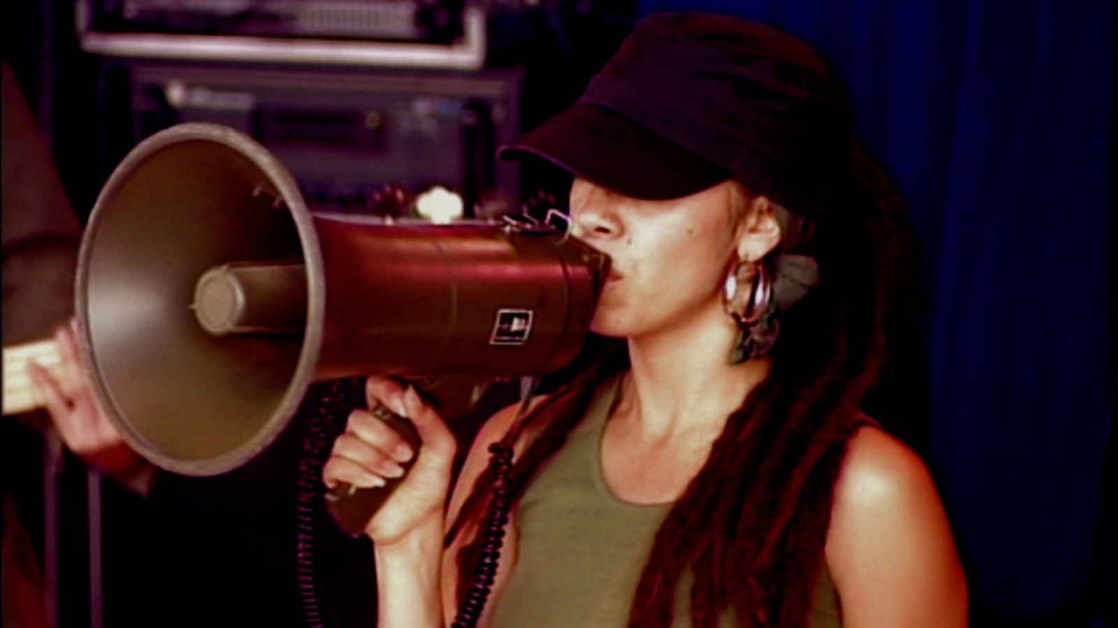 Woman with a megaphone to her mouth and hat on.