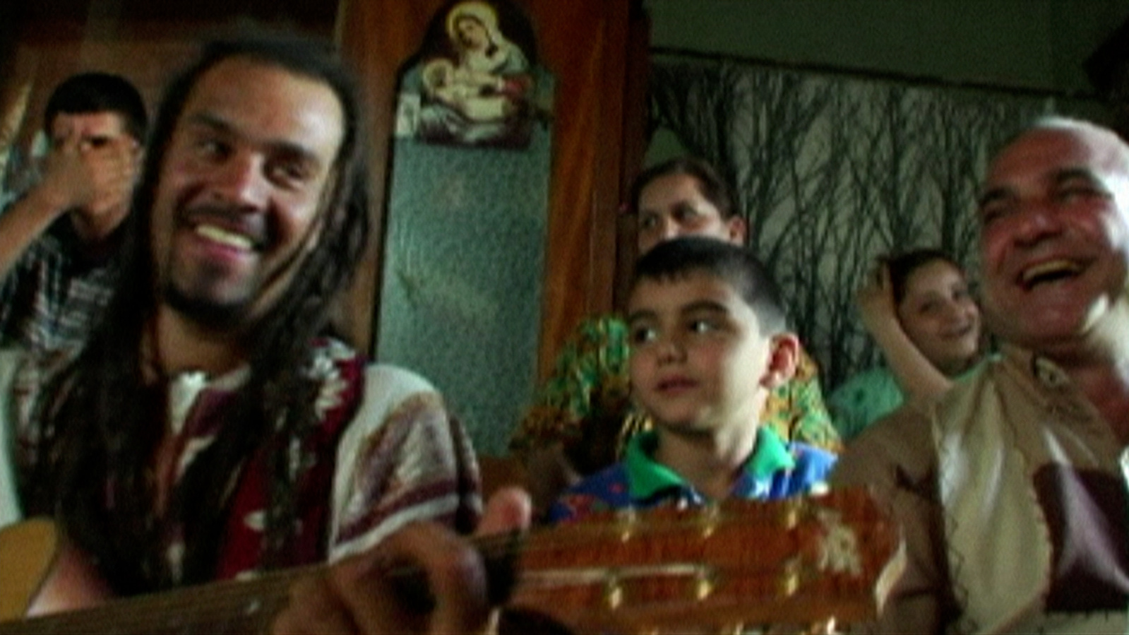 Michael Franti in Iraq playing guitar with children.