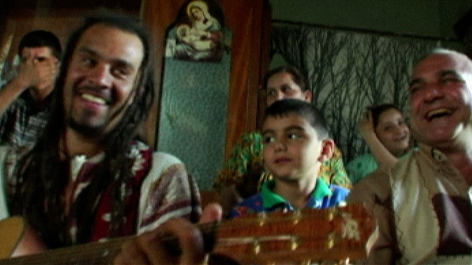 Michael Franti in Iraq playing guitar with children.