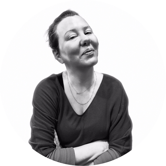 Black and white photo of a woman smiling with her arms crossed.