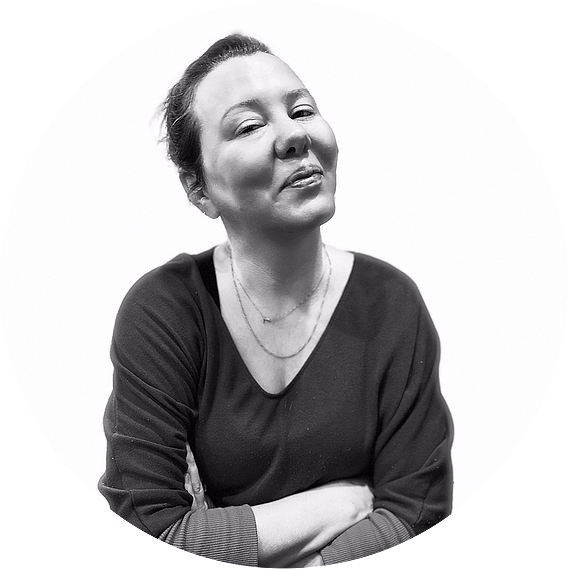Black and white photo of a woman smiling with her arms crossed.
