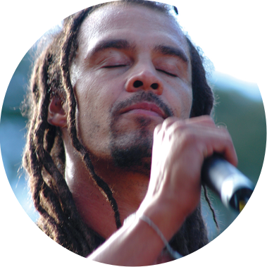 Michael Franti, musician, holding a microphone with eyes closed.