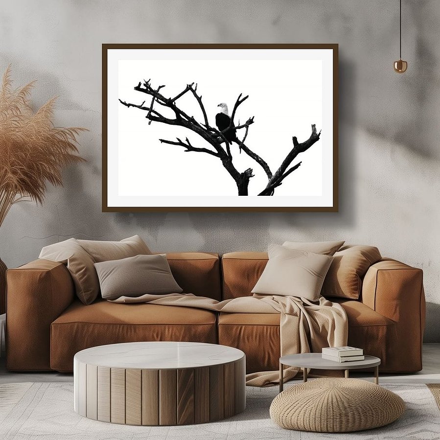 Black and white photograph of an African fish eagle perched in a bare tree, surveying the horizon. Its bold silhouette and striking contrast capture the eagle’s power, elegance, and watchful presence.