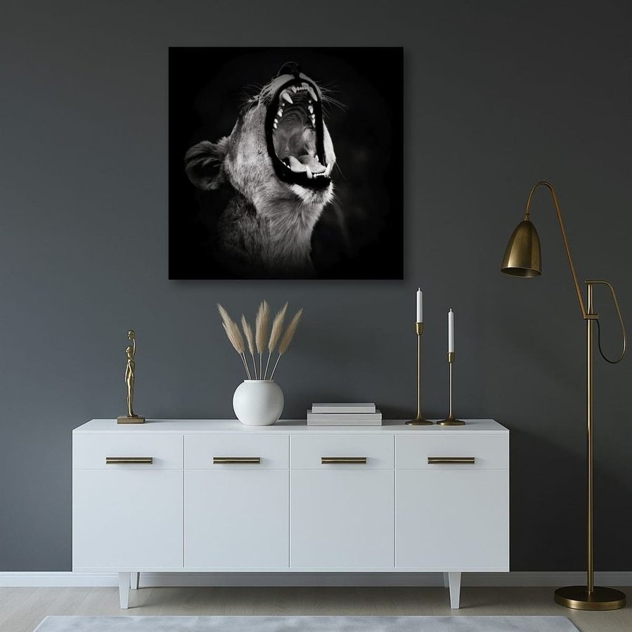 Powerful black and white side-profile photograph of a lioness mid-roar. Captured against a dark backdrop, this fine art wildlife image highlights her muscular form, fierce expression, and primal energy—an emotive portrait of strength and wild beauty.