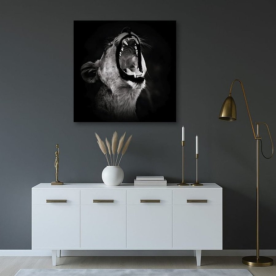 Powerful black and white side-profile photograph of a lioness mid-roar. Captured against a dark backdrop, this fine art wildlife image highlights her muscular form, fierce expression, and primal energy—an emotive portrait of strength and wild beauty.