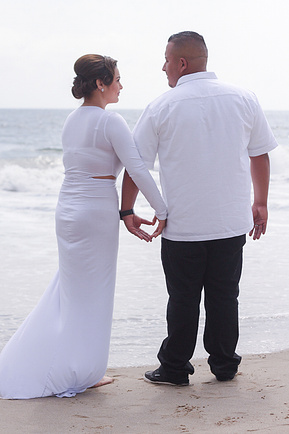 Engagement photograph, couple on the beach hands creating a heart. 
