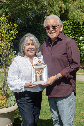 Elderly couple holding a photograph from their wedding ceremony. 