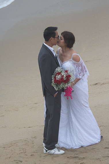Newly wed couple kissing on the beach. 